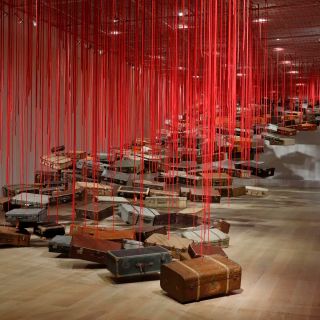 Shiota Chiharu, Accumulation - Searching for the Destination (2014-2019; valigie, motore e corda rossa, dimensioni variabili). Veduta dell’installazione presso la mostra Shiota Chiharu: The Soul Trembles, Mori Art Museum, Tokyo, 2019. Foto: Kioku Keizo. Su concessione di Mori Art Museum, Tokyo