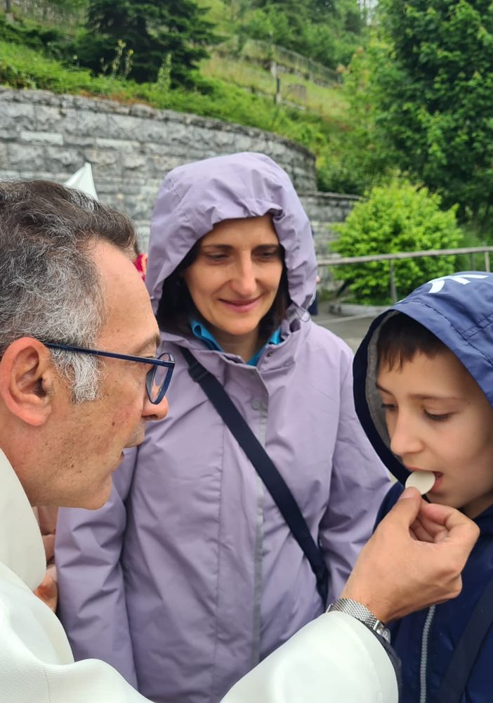 Don Isidoro Mercuri Giovinazzo offre la comunione a un bimbo sul sagrato di Lourdes