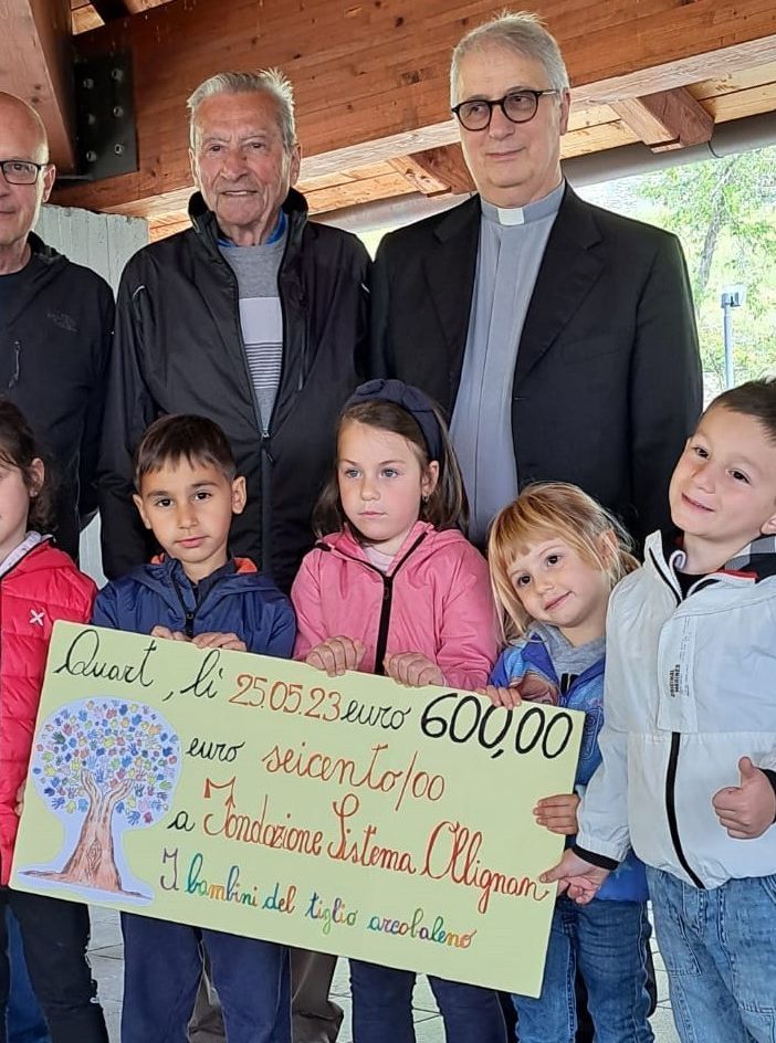 Assegno consegnato dal presidente della Cooperativa Scolastica, Stefano Occhipinti (secondo da sinistra), dal vicepresidente Noah Cilea (ultimo da sinistra), dai Consiglieri  Vittoria Belcastro Capuccini (prima da sinistra),Serena Bergonzo (in centro),Matilde Santomassimo (quart'ultima da sinistra). Dietro da sn il direttore di Fondazione Sistema Ollignan Onlus, René Benzo, il presidente, Gianfranco Trevisan e il presidente della Scuola Paritaria Sant'Orso Don Aldo Armellin