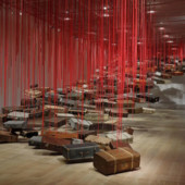 Shiota Chiharu, Accumulation - Searching for the Destination (2014-2019; valigie, motore e corda rossa, dimensioni variabili). Veduta dell’installazione presso la mostra Shiota Chiharu: The Soul Trembles, Mori Art Museum, Tokyo, 2019. Foto: Kioku Keizo. Su concessione di Mori Art Museum, Tokyo