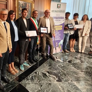Da sn l'assessore regionale ai Trasporti, Luigi Bertschy; l'assessora al Turismo di Doues, Corinne Cuaz; il vicesindaco di Doues, Daniel Diemoz; il sindaco di Doues, Giorgio Abram; il Presidente della Regione, Renzo Testolin; i genitori della minore di Doues, la Coordinatrice dell’istituzione scolastica Grand Combin, Simona d’Agostino, il Presidente di Aice Valle d’Aosta ODV, Manuele Amateis