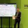 ll dottor Stefano Okolicsanyi alla UEG Week 2026 di Barcellona accanto al poster della ricerca del progetto 5000genomi@VdA, con l'attestato del Best Abstract Presentation Prize
